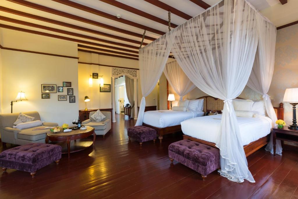 a bedroom with two beds and a living room at The Luang Say Residence in Luang Prabang
