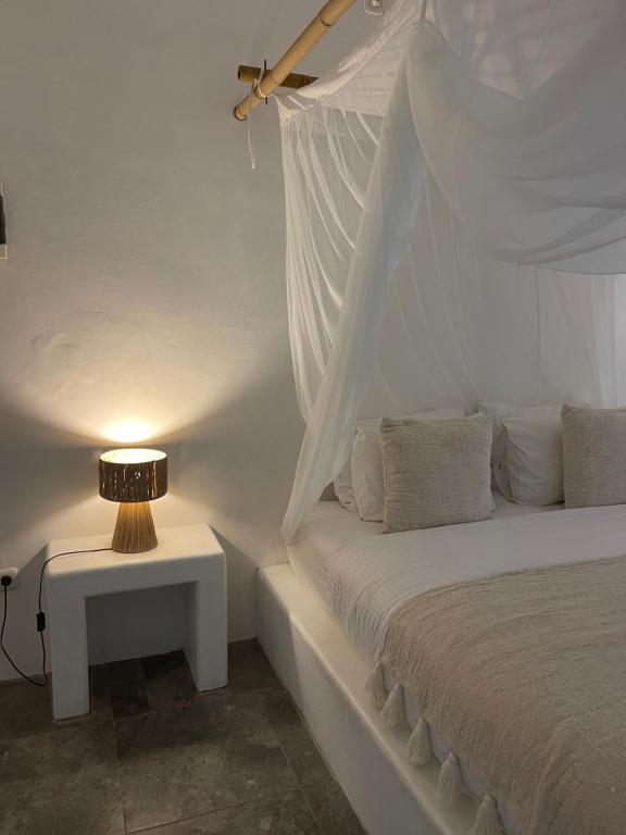 a bed with a white canopy with a table with a lamp at Cabana in Gili Islands