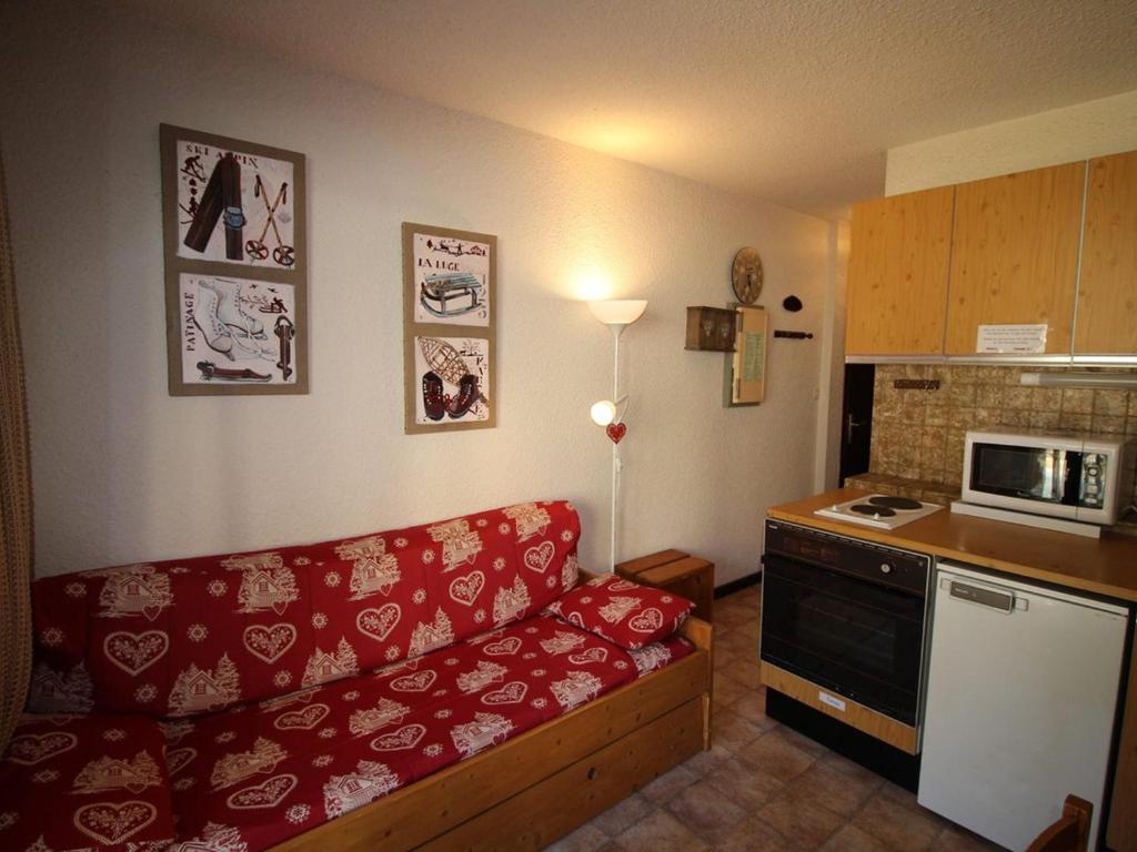 un salon avec un canapé rouge et une cuisine dans l'établissement Appartement 2 pièces, 300m des pistes, parking, animaux admis - Auris en Oisans - FR-1-297-44, à Auris