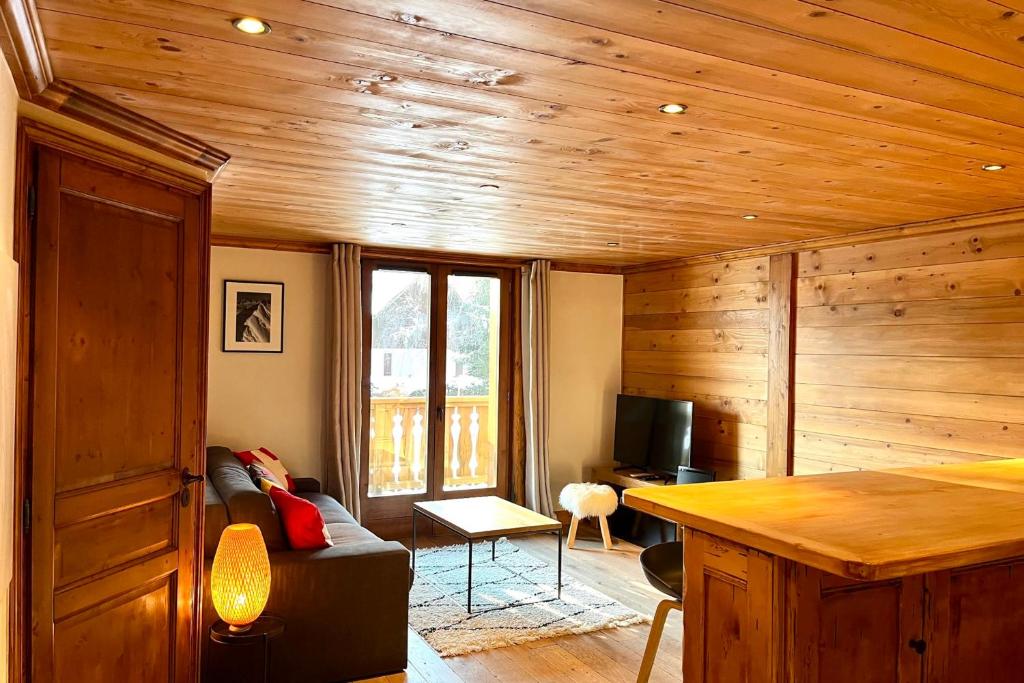 sala de estar con paredes de madera, sofá y TV en Chic And Cosy Apt With Balcony In Megeve en Megève