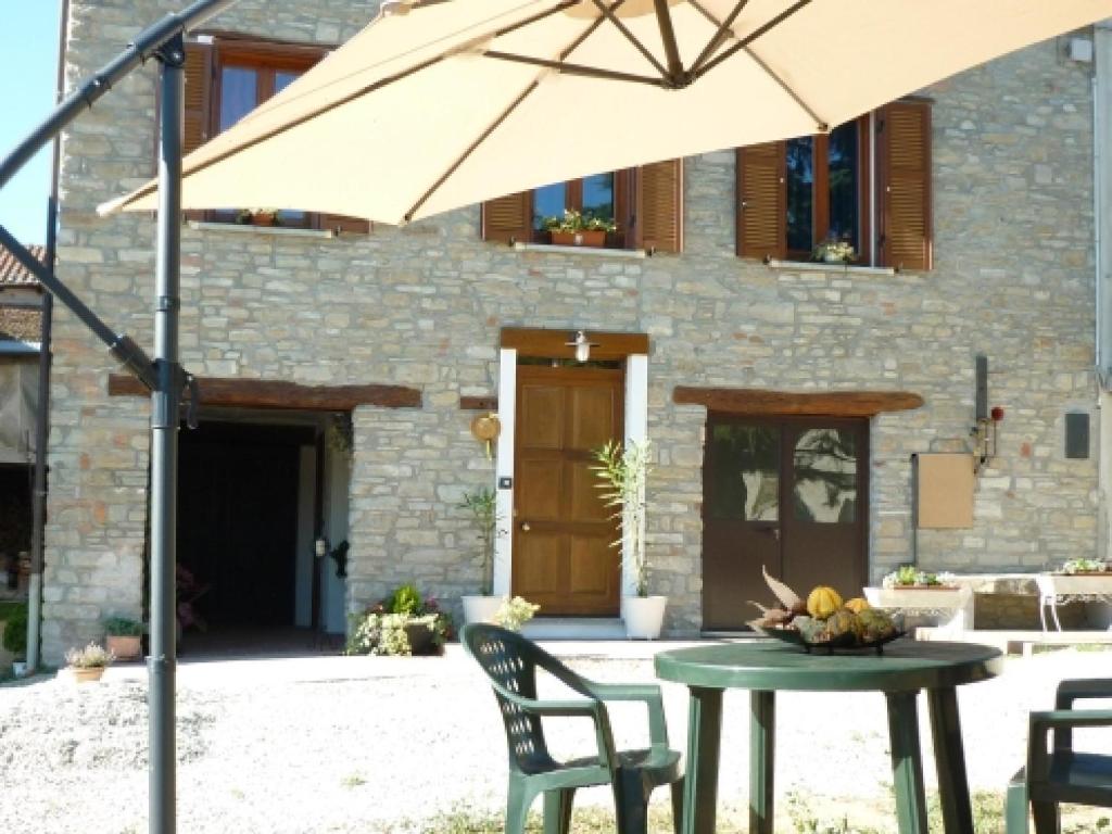 a table with an umbrella in front of a building at Il Grappolo In Langa in Monastero Bormida