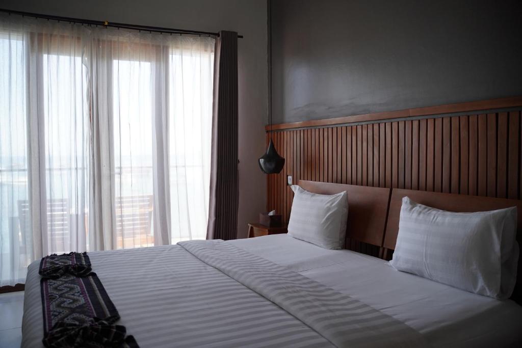 a bedroom with a large bed with a large window at Escape Bajo in Labuan Bajo