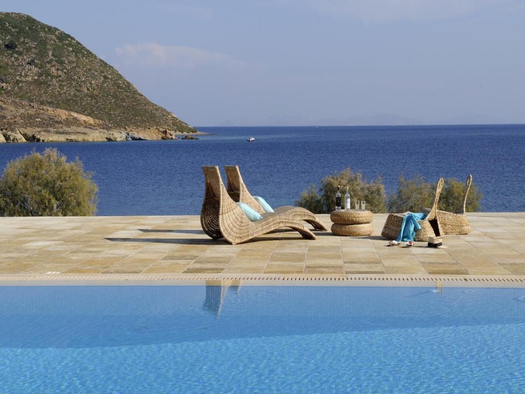 einen Pool mit Korbstühlen neben dem Wasser in der Unterkunft Onar Patmos in Grikos