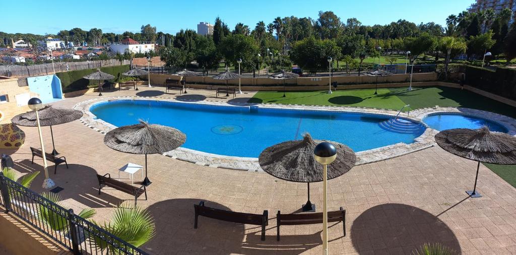 einen Pool mit Sonnenschirmen und einen Golfplatz in der Unterkunft Costa Azahar II Nº 1041 in Oropesa del Mar
