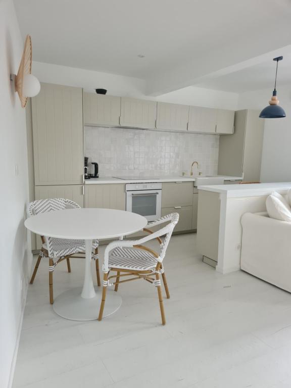 a white kitchen with a table and chairs in it at Victoire Saphir 203 climatisé hôtel de ville in Saint-Dizier