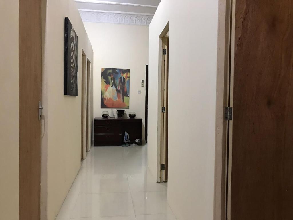 a hallway with white walls and white tile floors at Backpackers Place - Central Bus Terminal in Abu Dhabi