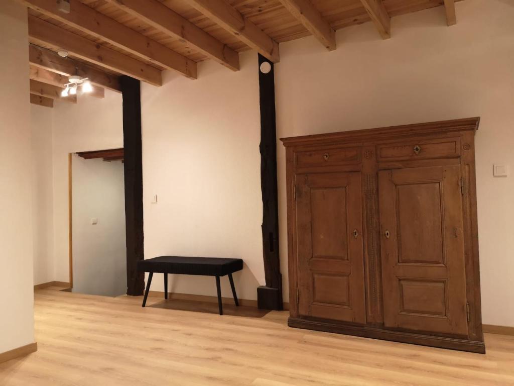 an empty room with a wooden cabinet and a stool at Gîte Les trois charmes in Gouvy