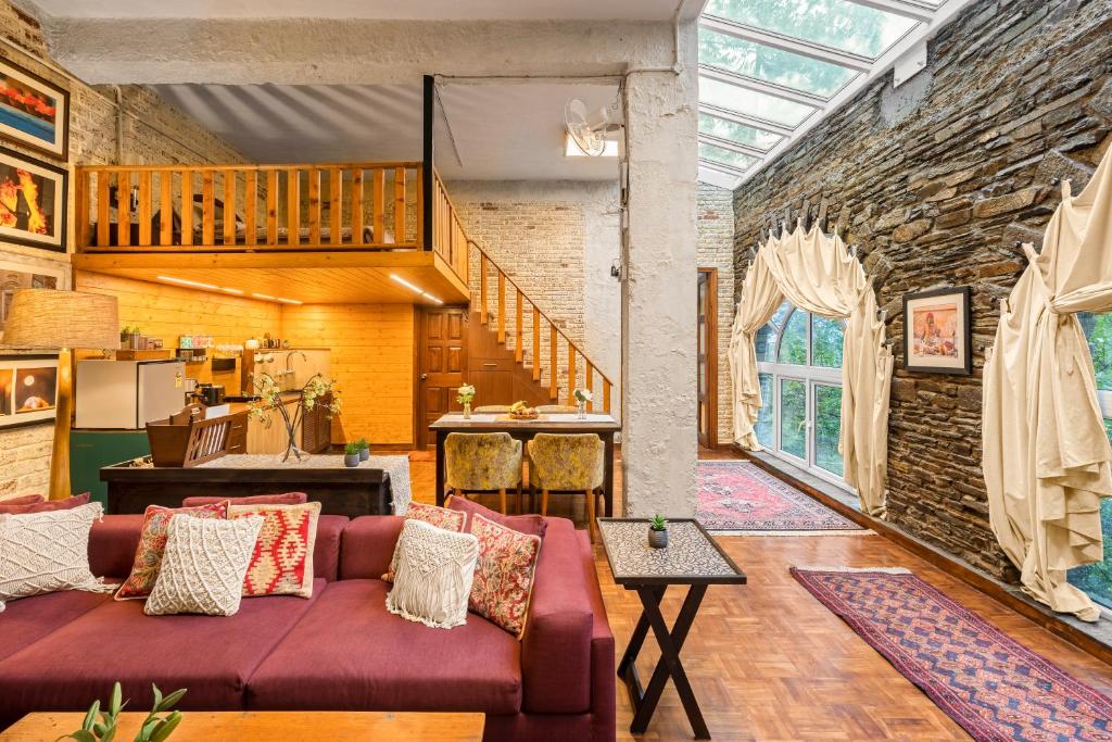 - un salon avec un canapé rouge et un mur en briques dans l'établissement SaffronStays Ekam Walnut Suite, Chail, à Kandāghāt