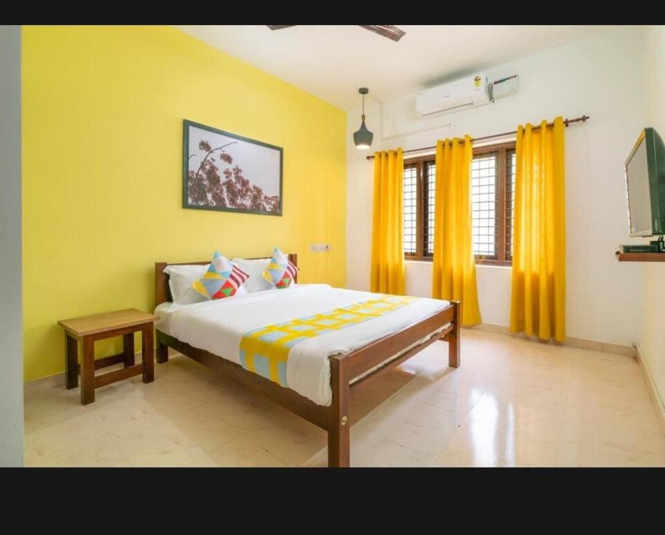 sypialnia z dużym łóżkiem z żółtymi ścianami w obiekcie Tharayil Apartments w mieście Koczin