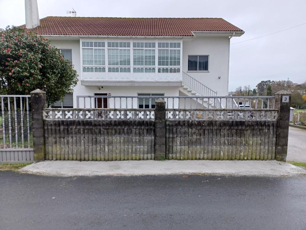 une clôture devant une maison blanche dans l'établissement Acogedora Casa de campo- BAJO con finca-, à Neda