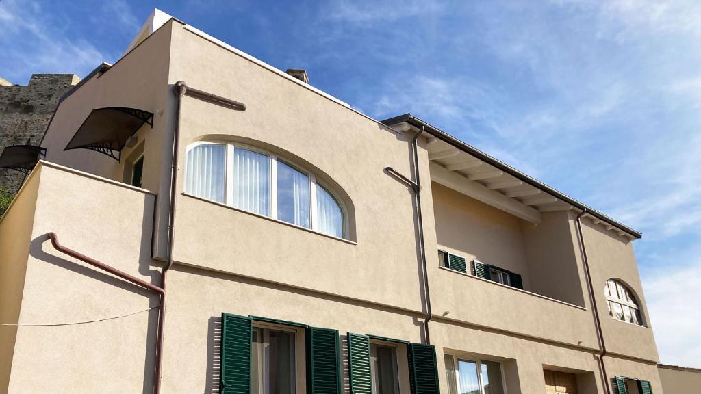 a tan building with green shutters on it at Falconetta Luxury House in Portoferraio