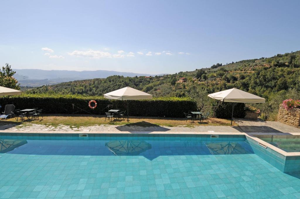 a swimming pool with umbrellas and a view of a mountain at Agriturismo La Casella in Castelfranco di Sopra