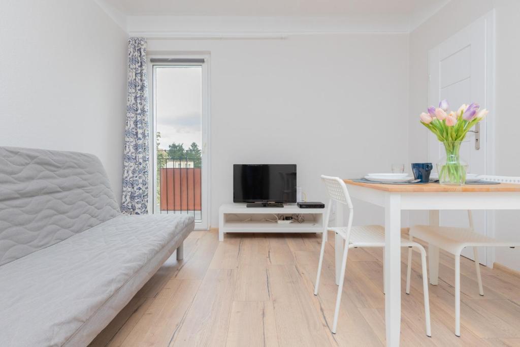 a white living room with a table and a tv at Apartment Beachy Dream by Renters in Gdańsk