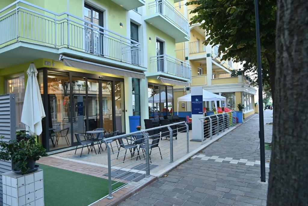a building with tables and chairs on a street at Hotel ITALY in Misano Adriatico