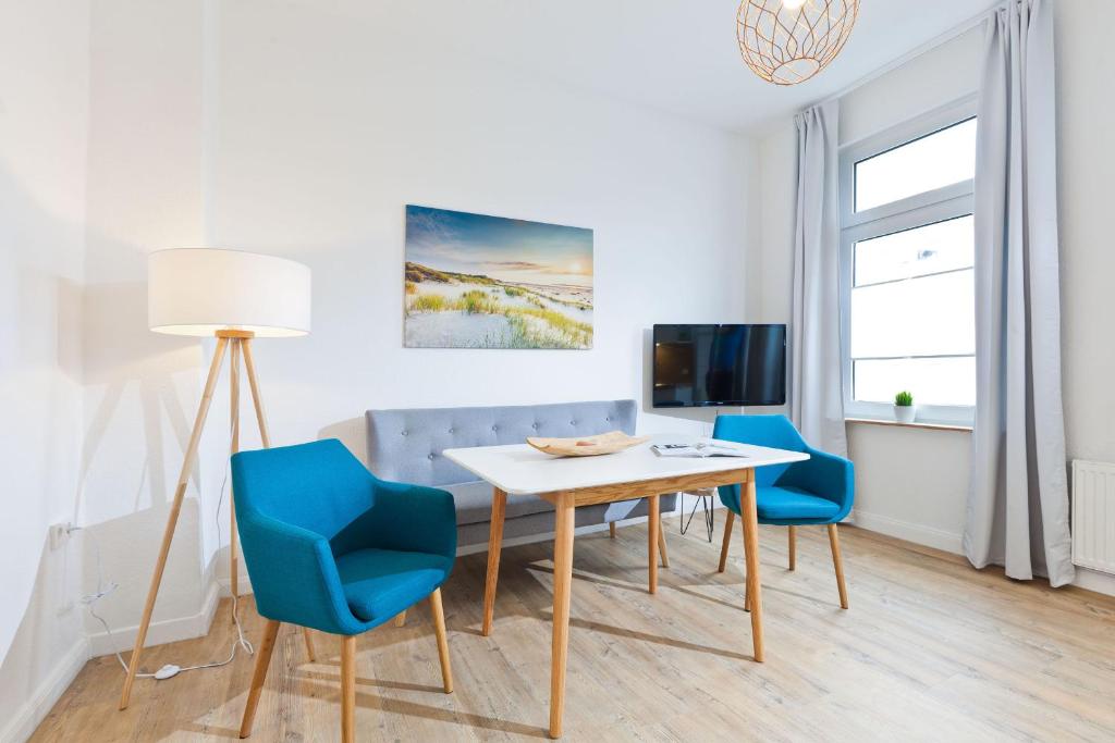 ein Wohnzimmer mit einem Tisch und 2 blauen Stühlen in der Unterkunft Haus Menno Janssen - Ferienwohnung Bella in Norderney