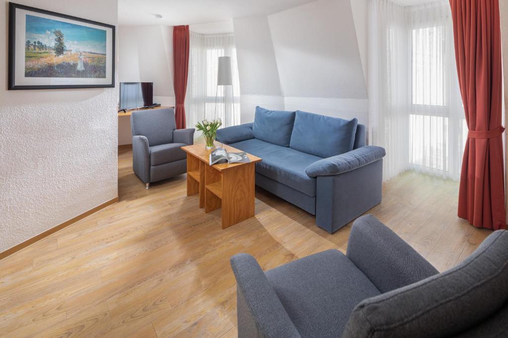 ein Wohnzimmer mit einem blauen Sofa und Stühlen in der Unterkunft Die Kogge - Wohnung 9 in Norderney