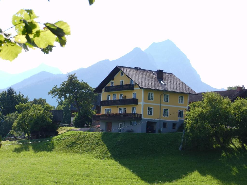 ein gelbes Haus auf einem Hügel mit Bergen im Hintergrund in der Unterkunft Hinterramsebn in Vorderstoder