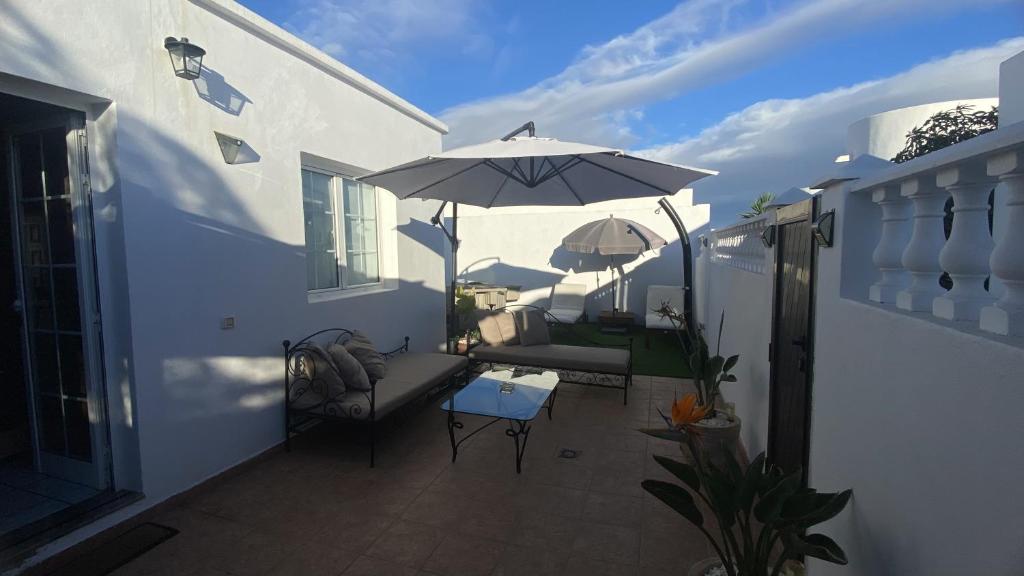 eine Terrasse mit einem Sonnenschirm, einem Tisch und Stühlen in der Unterkunft La Duomo di Vulcano in Playa Honda