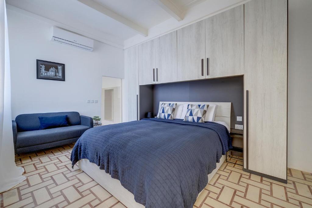 a bedroom with a large bed and a blue couch at Idyllic Apartment close to Valletta in Il-Furjana