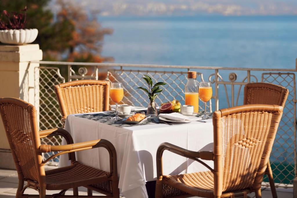 un tavolo con cibo e succo d'arancia su un balcone di Hotel Lovran a Lovran (Laurana)