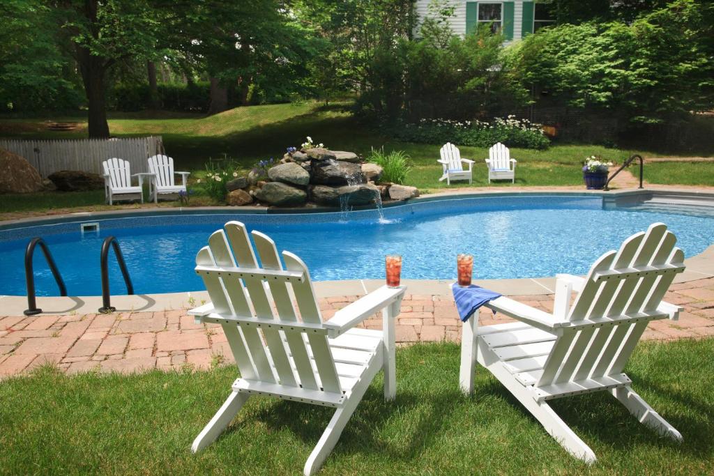 two white chairs sitting next to a swimming pool at Hampton Terrace Inn in Lenox