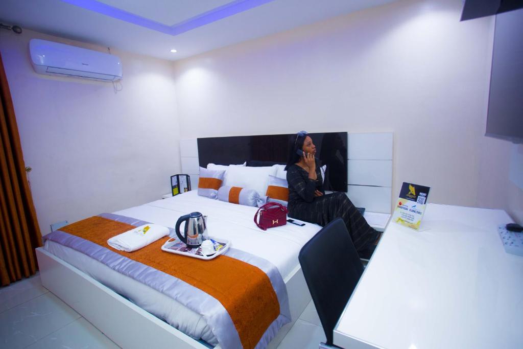 a woman sitting on a bed in a room at Appleville Suites in Ikeja
