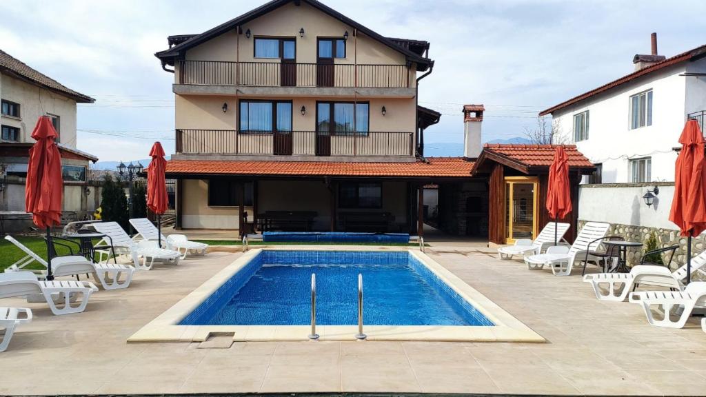 uma casa com piscina em frente a um edifício em Къща за гости - Вила Сидона em Banya
