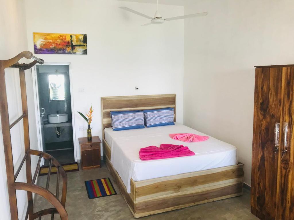 a bedroom with a bed with pink sheets and blue pillows at fantasea villa in Unawatuna