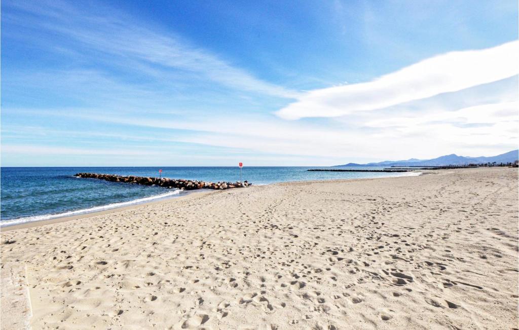 a sandy beach with a pier in the ocean at Amazing Apartment In Saint Cyprien Plage With Wifi in Saint-Cyprien-Plage