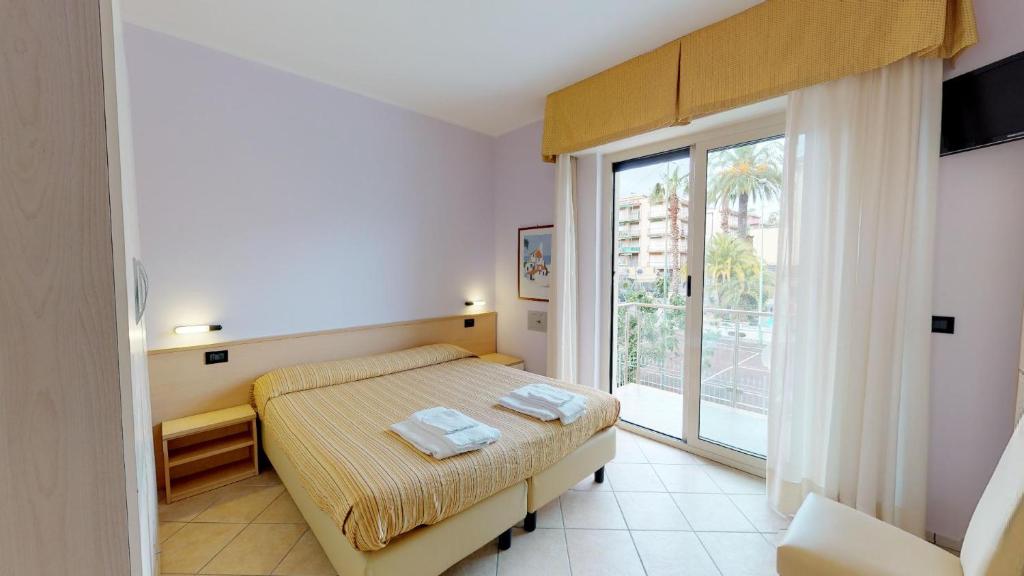 een slaapkamer met een bed en een groot raam bij Miriam Hotel & Residence in Pietra Ligure