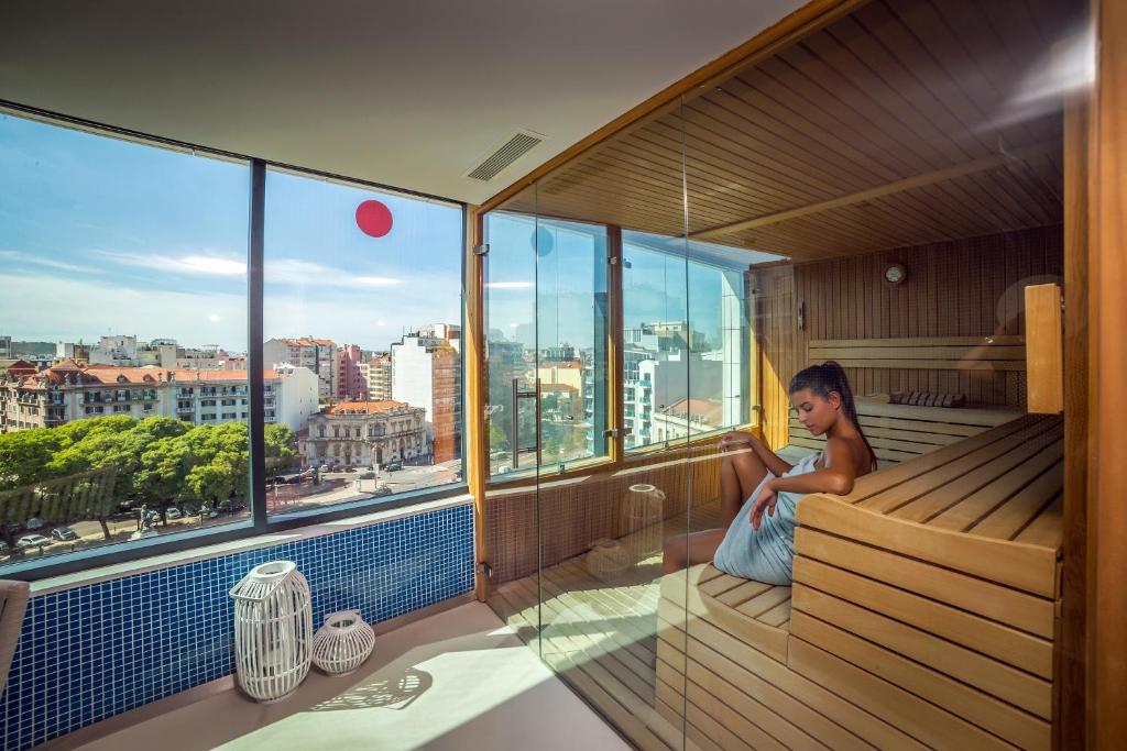 una mujer sentada en una sauna con vistas a la ciudad en EVOLUTION Lisboa Hotel, en Lisboa