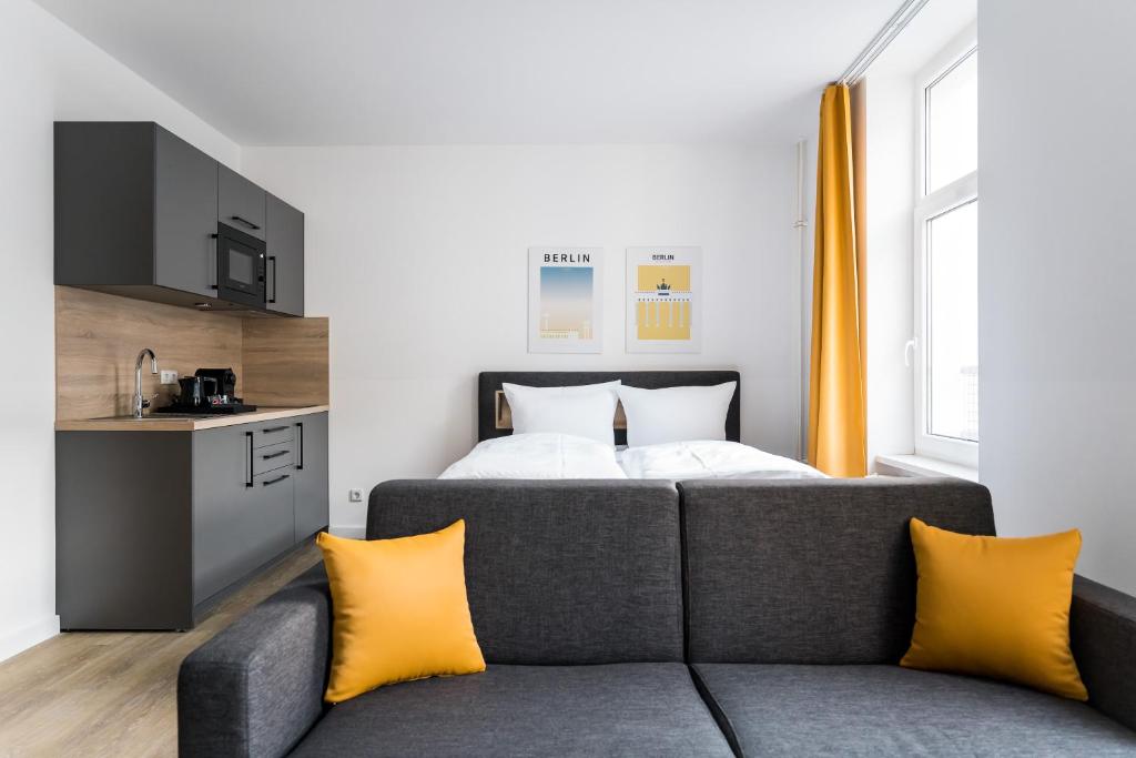 ein Schlafzimmer mit einem Bett und einem Sofa mit gelben Kissen in der Unterkunft Homaris Boxi Studios in Berlin