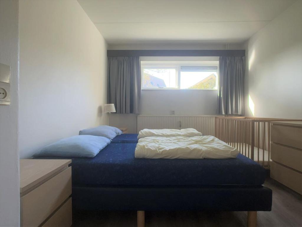 a bedroom with a bed with blue sheets and a window at Wijk de Brabander 61 in Cadzand