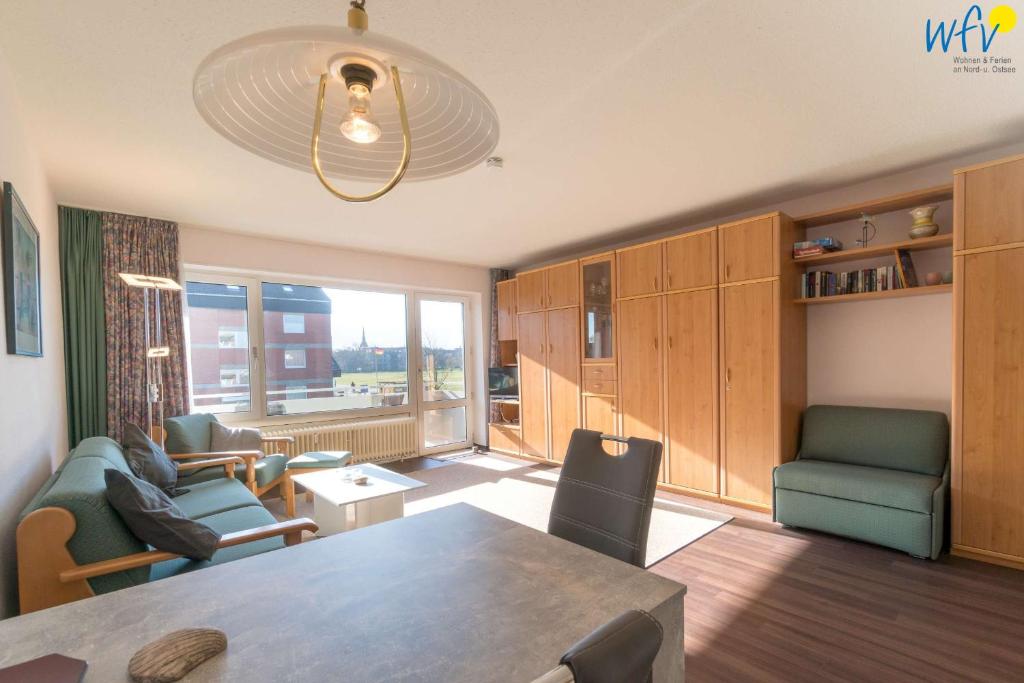 ein Wohnzimmer mit einem Tisch und Stühlen sowie einem großen Fenster in der Unterkunft Holiday Residenz Ferienwohnung Leuchtturmblick in Borkum