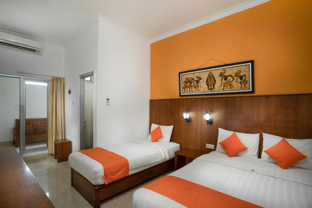 a hotel room with two beds with orange walls at Hotel Poncowinatan - Tugu in Yogyakarta