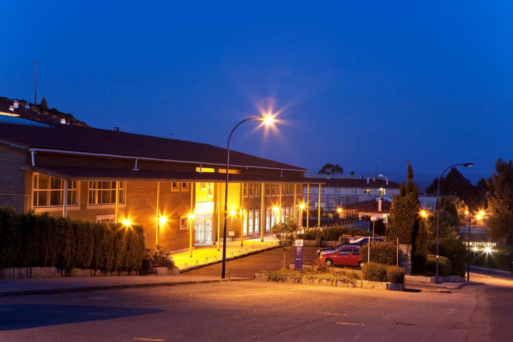 ein Gebäude mit Straßenbeleuchtung neben einem Parkplatz in der Unterkunft Hotel Rialta in Culleredo
