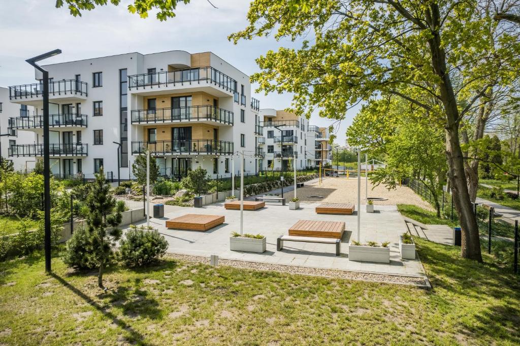 an apartment building with benches in a park at BlueApart Apartamenty Nexo in Puck
