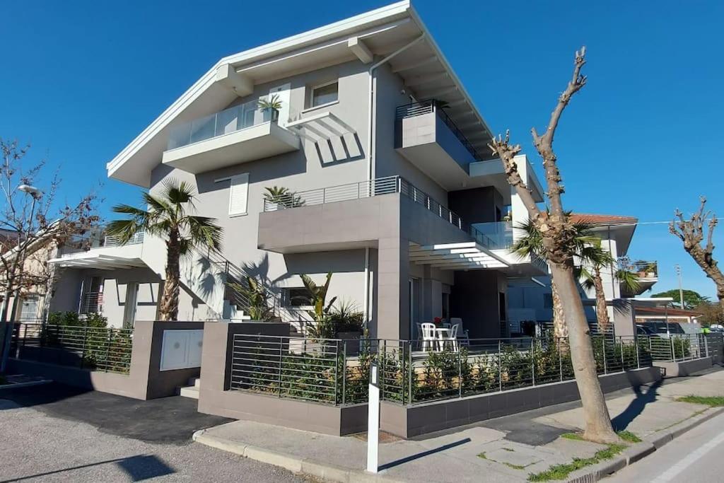 a white building with palm trees in front of it at Appartamento Garden in Riccione