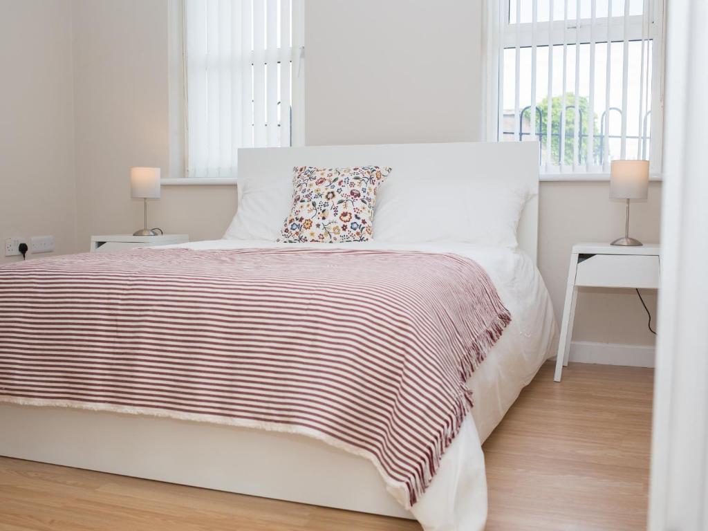 a white bedroom with a white bed and two windows at PG McQuaid Suite in Dungannon