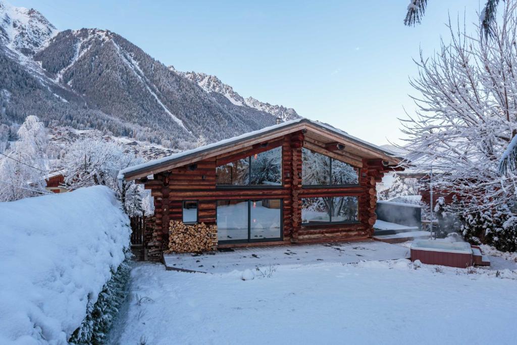 een blokhut in de sneeuw met bergen op de achtergrond bij Chalet des Cimes - Chamonix All Year in Chamonix-Mont-Blanc