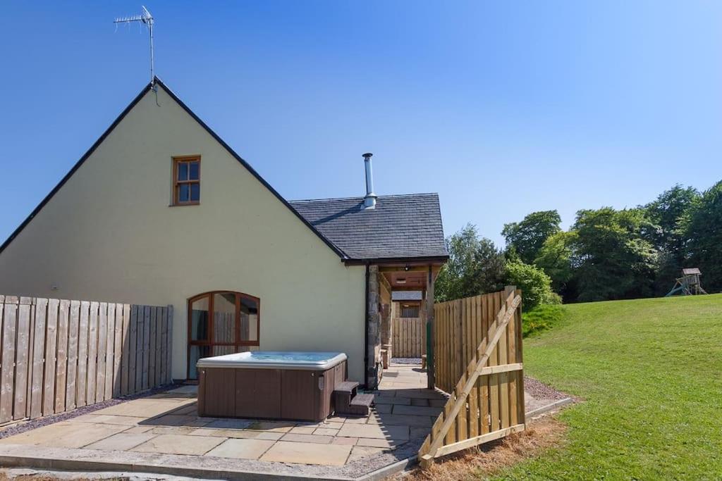 a small white house with a wooden fence at Beech Cottage at Williamscraig Holiday Cottages in Linlithgow