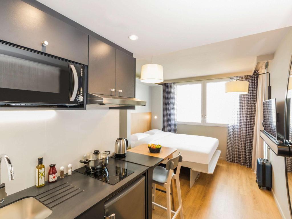 een kamer met een keuken en een slaapkamer met een bed bij Aparthotel Adagio access Palaiseau Saclay in Palaiseau