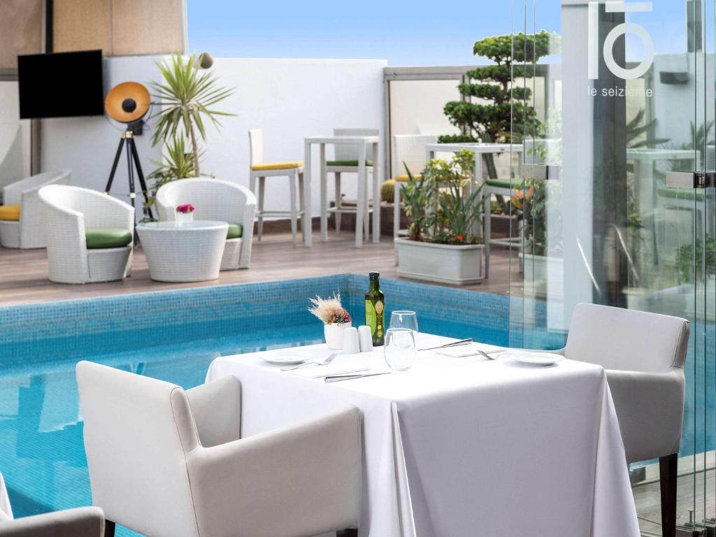 a table with white chairs next to a pool at Mövenpick Hotel Casablanca in Casablanca