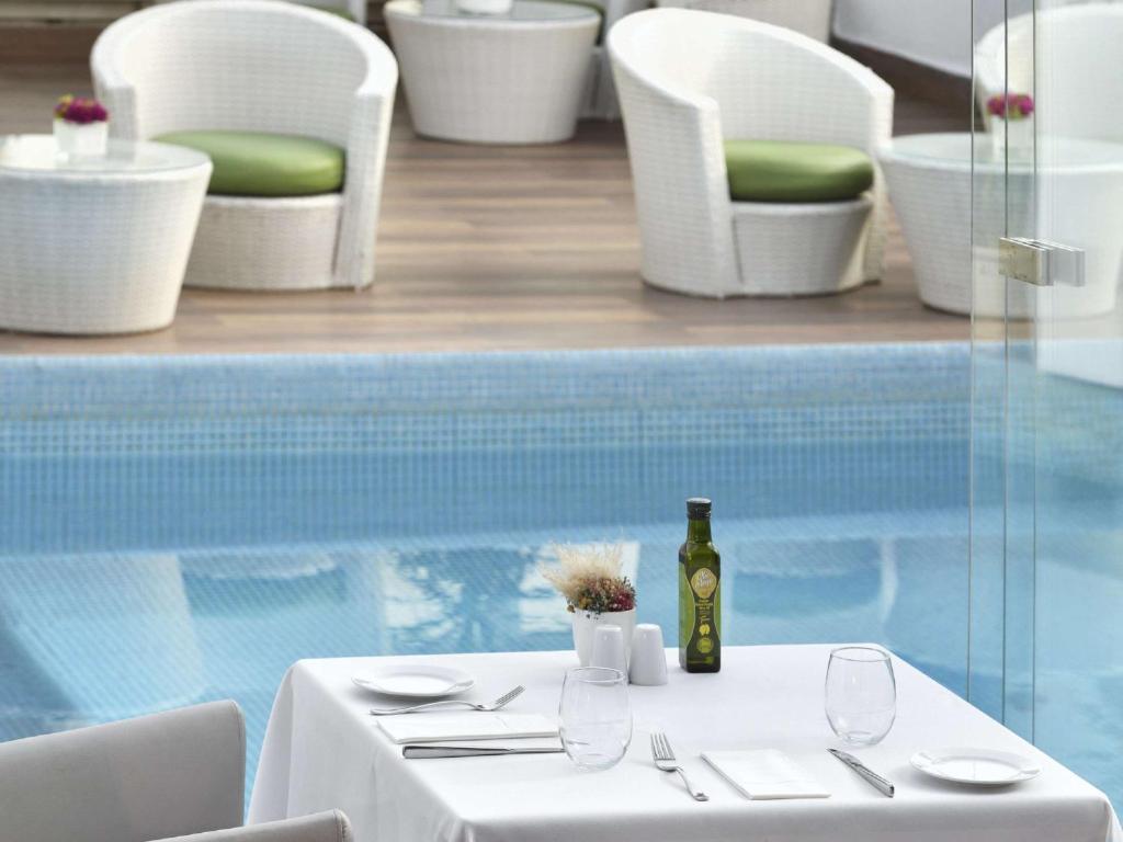 a table with a bottle of wine next to a pool at Mövenpick Hotel Casablanca in Casablanca
