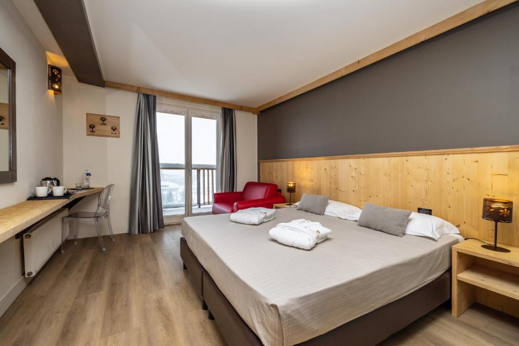 a bedroom with a large bed and a red chair at Hotel Piandineve in Passo del Tonale