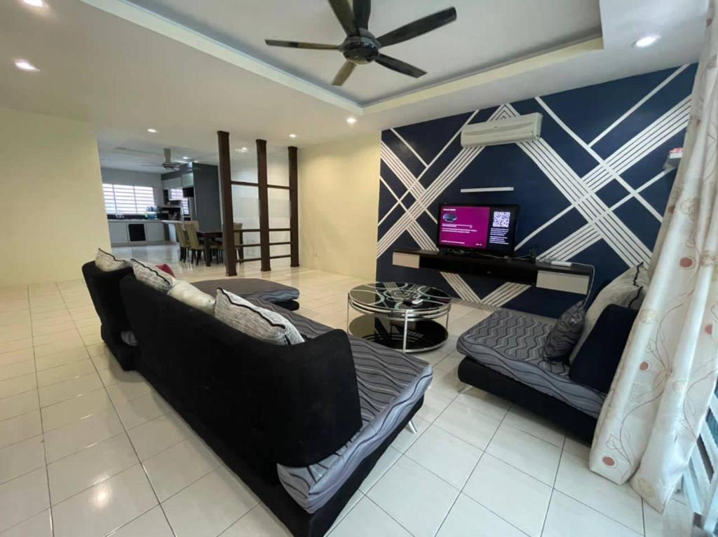 RJ Homey Guesthouse في سونغاي بيتاني: غرفة معيشة مع أريكة ومروحة سقف