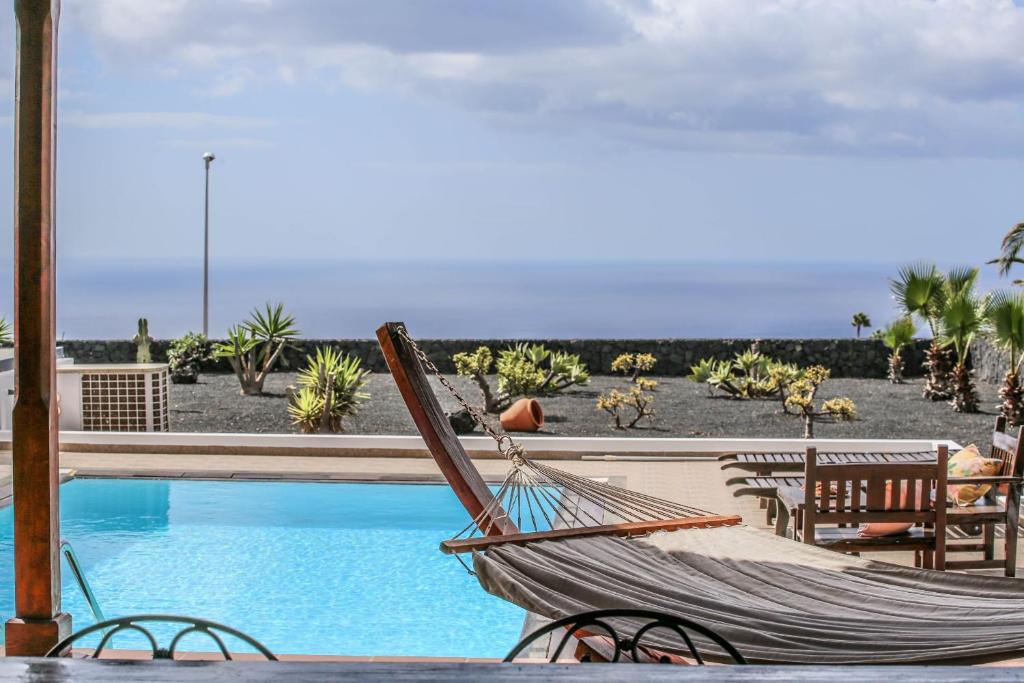 a hammock sitting next to a swimming pool at Villa Horizon Sunset y Ocean Lanzarote in Mácher
