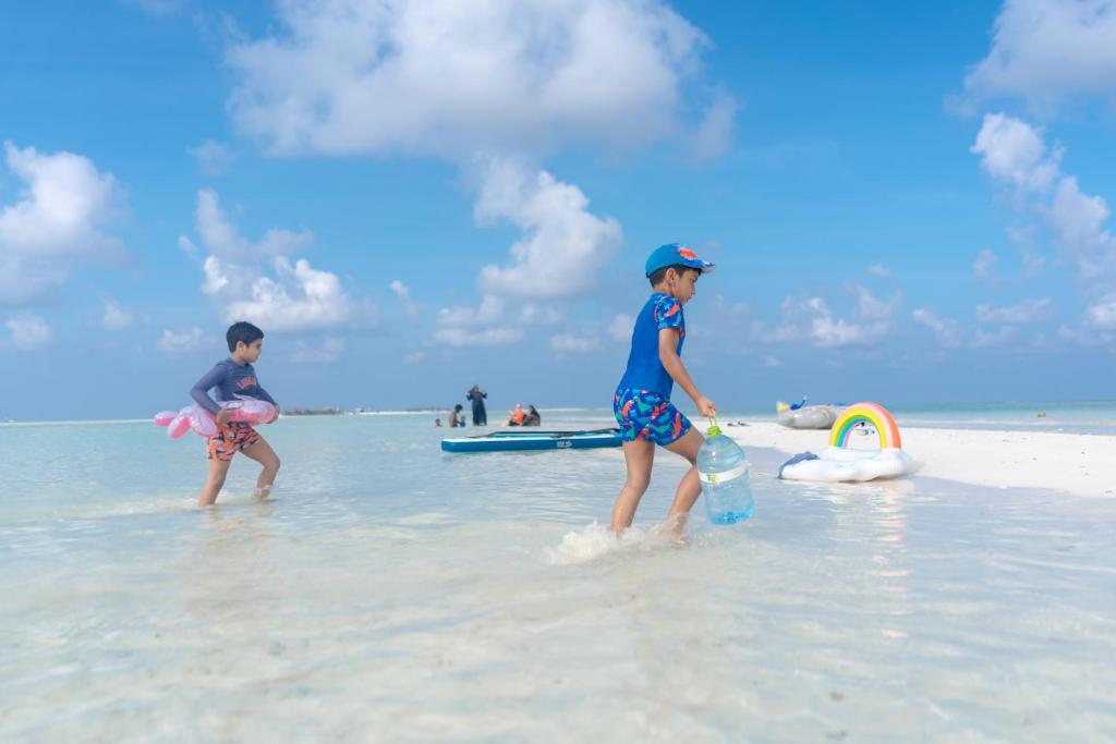 two children playing in the water on the beach at Brickwood Ganduvaru Private Villas in Rasdu