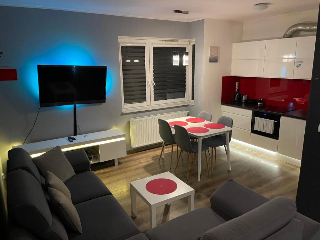 a living room with a couch and a table and a kitchen at Gdynia Apartament 42 m z miejscem w Garażu z Windą blisko centrum i morza in Gdynia