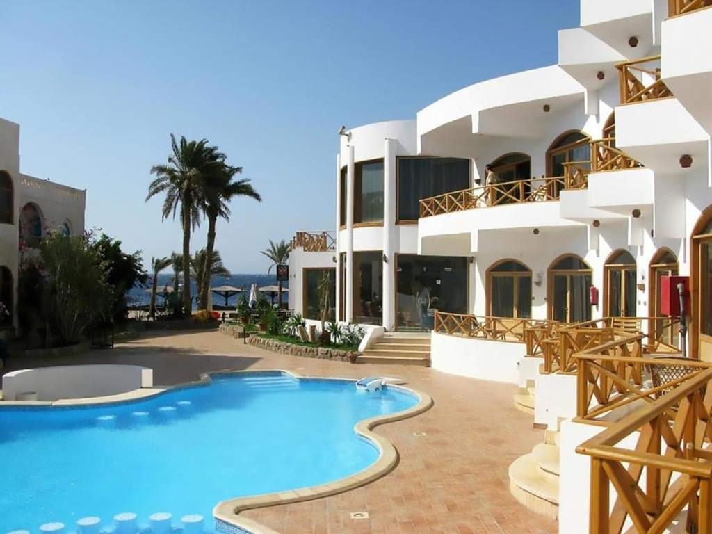 Red Sea Relax Hotel في دهب: منتجع فيه مسبح امام مبنى